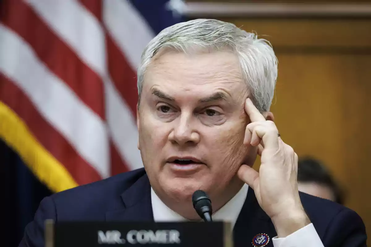 Gray-haired man speaking in front of a microphone with a United States flag in the background Gray-haired man speaking in front of a microphone with a United States flag in the background