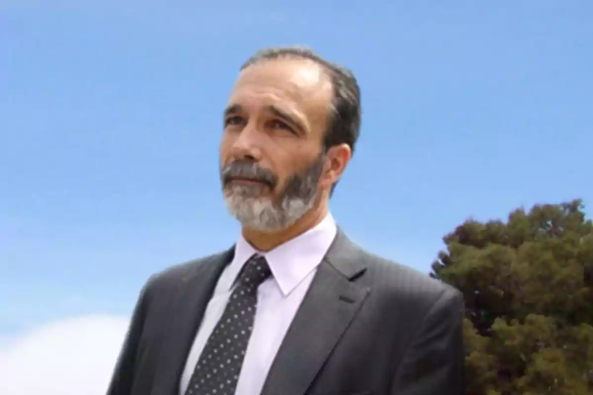 Gray-bearded man in a suit and tie standing outdoors with a blue sky in the background Gray-bearded man in a suit and tie standing outdoors with a blue sky in the background