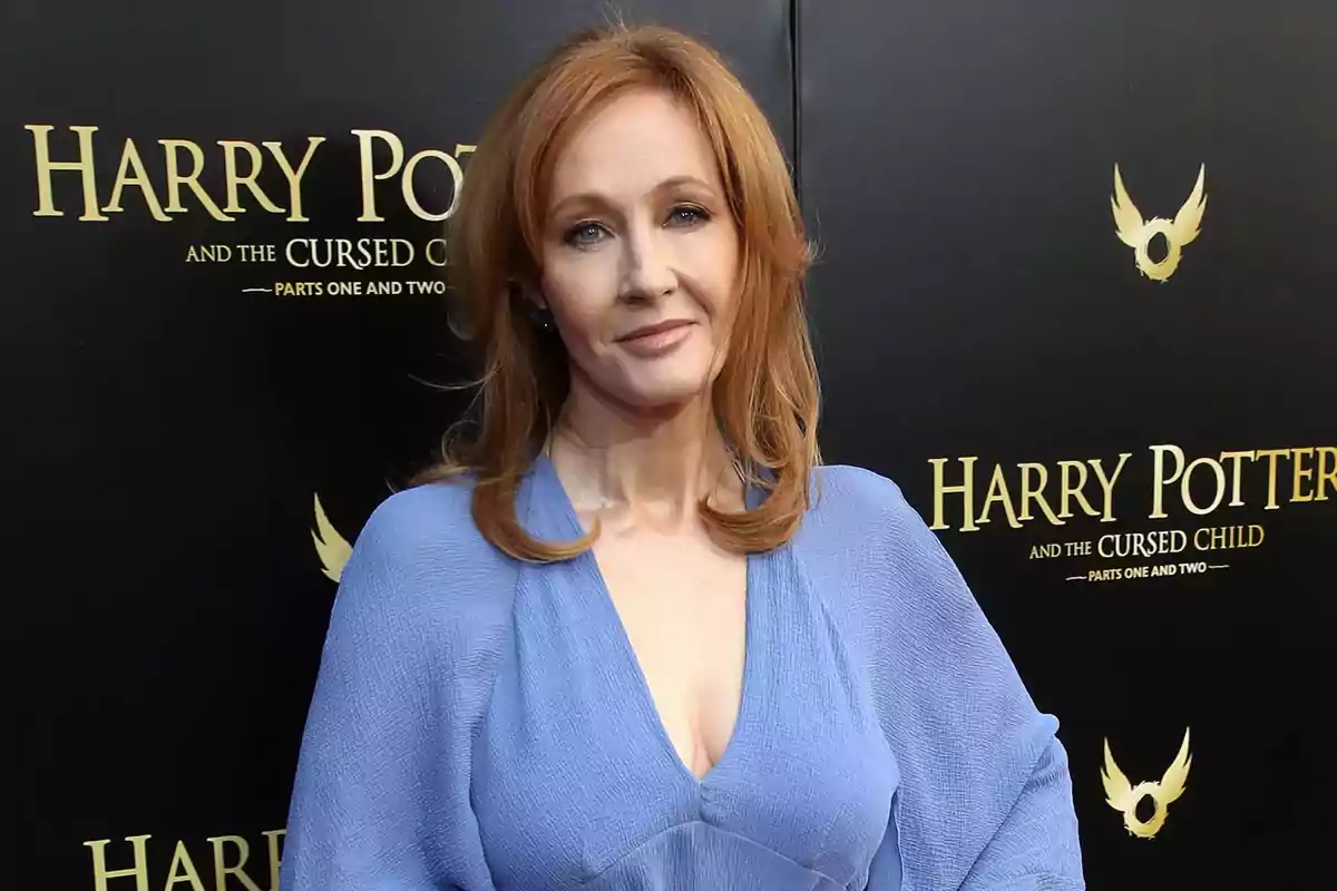 Red-haired woman in a light blue dress posing in front of a promotional backdrop for Harry Potter and the Cursed Child Red-haired woman in a light blue dress posing in front of a promotional backdrop for Harry Potter and the Cursed Child