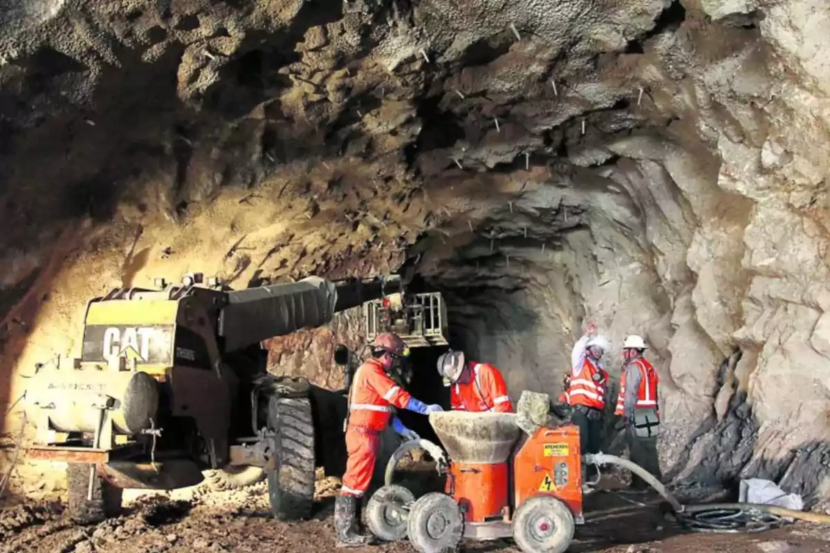 Trabajadores con equipo de seguridad operan maquinaria pesada dentro de un túnel en construcción