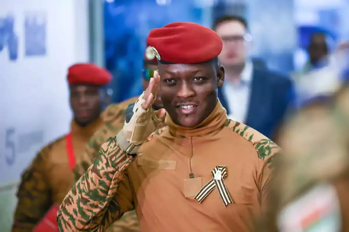 Soldado con boina roja y uniforme camuflado saluda mientras sonríe en un evento público Soldado con boina roja y uniforme camuflado saluda mientras sonríe en un evento público