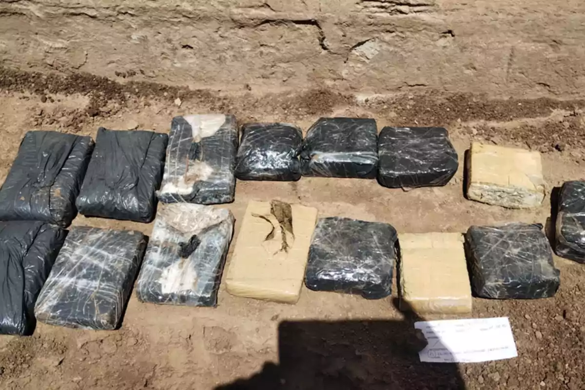 Packages wrapped in black plastic and duct tape placed on the ground next to a stone wall Packages wrapped in black plastic and duct tape placed on the ground next to a stone wall