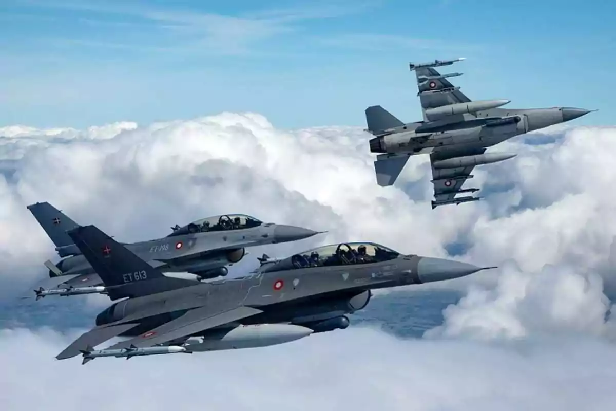 Tres aviones de combate F-16 vuelan en formación sobre un cielo con nubes blancas Tres aviones de combate F-16 vuelan en formación sobre un cielo con nubes blancas