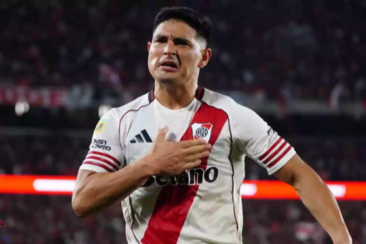 River Plate player celebrating a goal with his hand on his chest in a packed stadium
