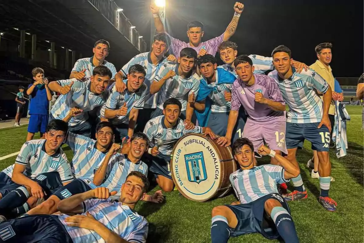 Soccer team players pose smiling on the field celebrating a victory next to a bass drum with the Racing Club crest. Soccer team players pose smiling on the field celebrating a victory next to a bass drum with the Racing Club crest.