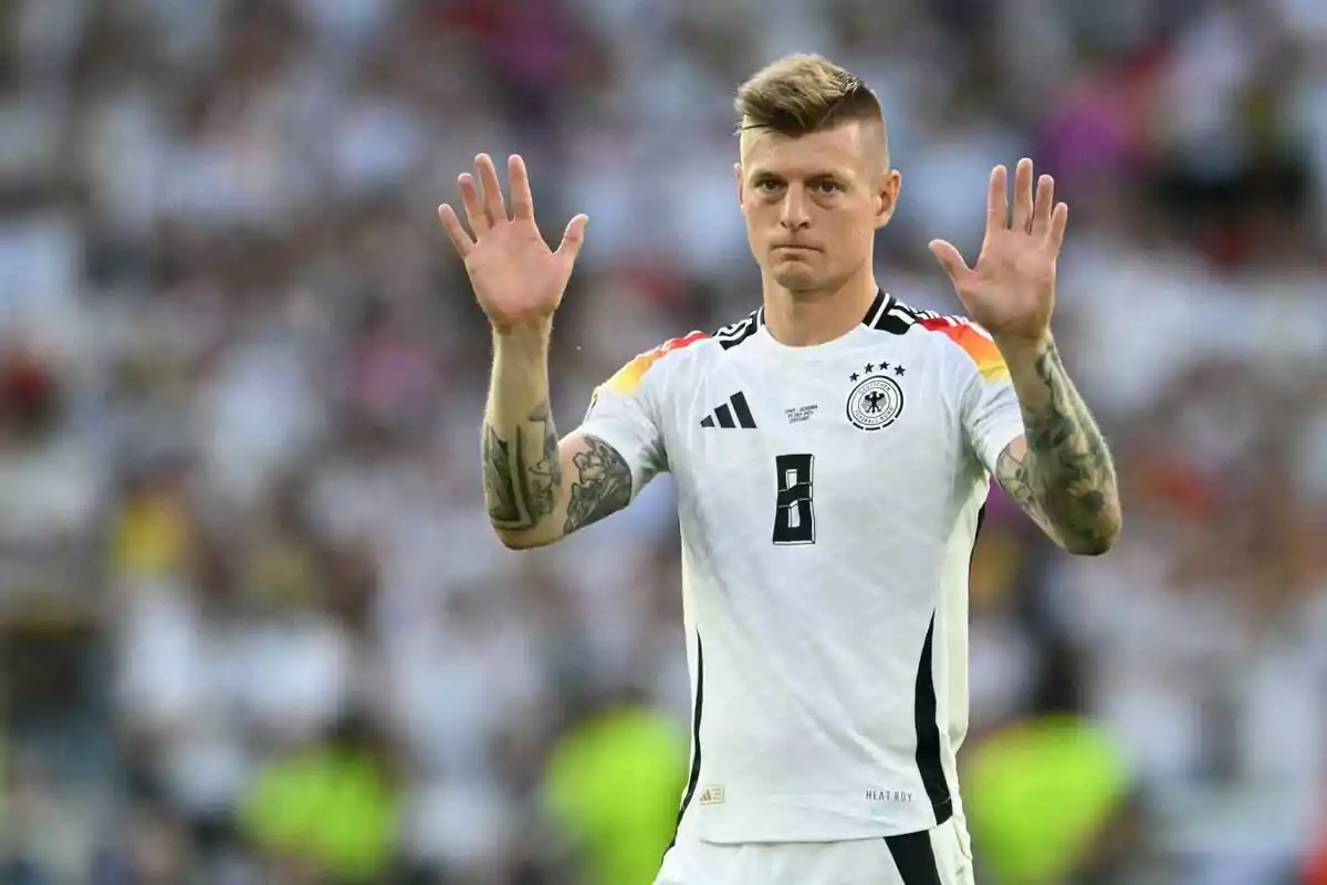 Futbolista con uniforme de Alemania levantando ambas manos durante un partido