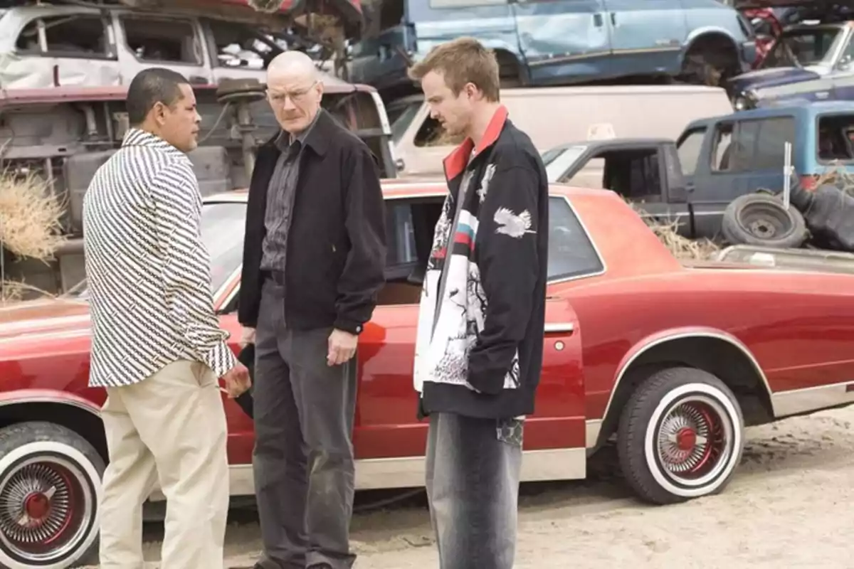 Tres hombres conversan junto a un auto rojo en un deshuesadero de autos Tres hombres conversan junto a un auto rojo en un deshuesadero de autos