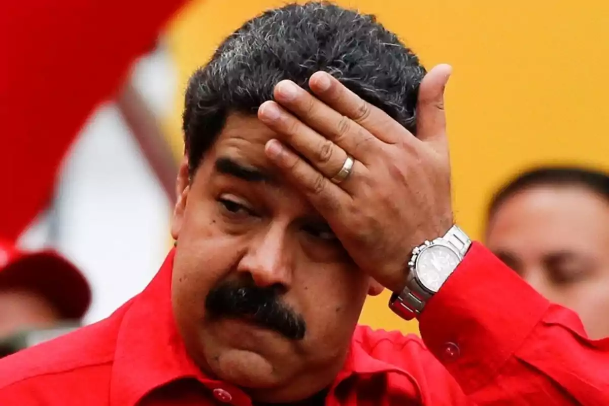 Man in a red jersey holding his hand to his forehead in a gesture of concern