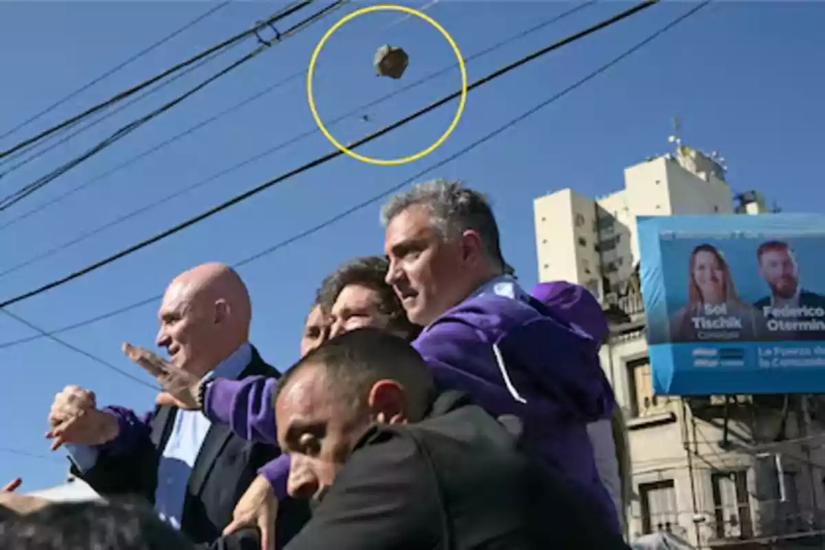 A group of people on the street protect themselves as a rock flies over them under a clear sky. A group of people on the street protect themselves as a rock flies over them under a clear sky.