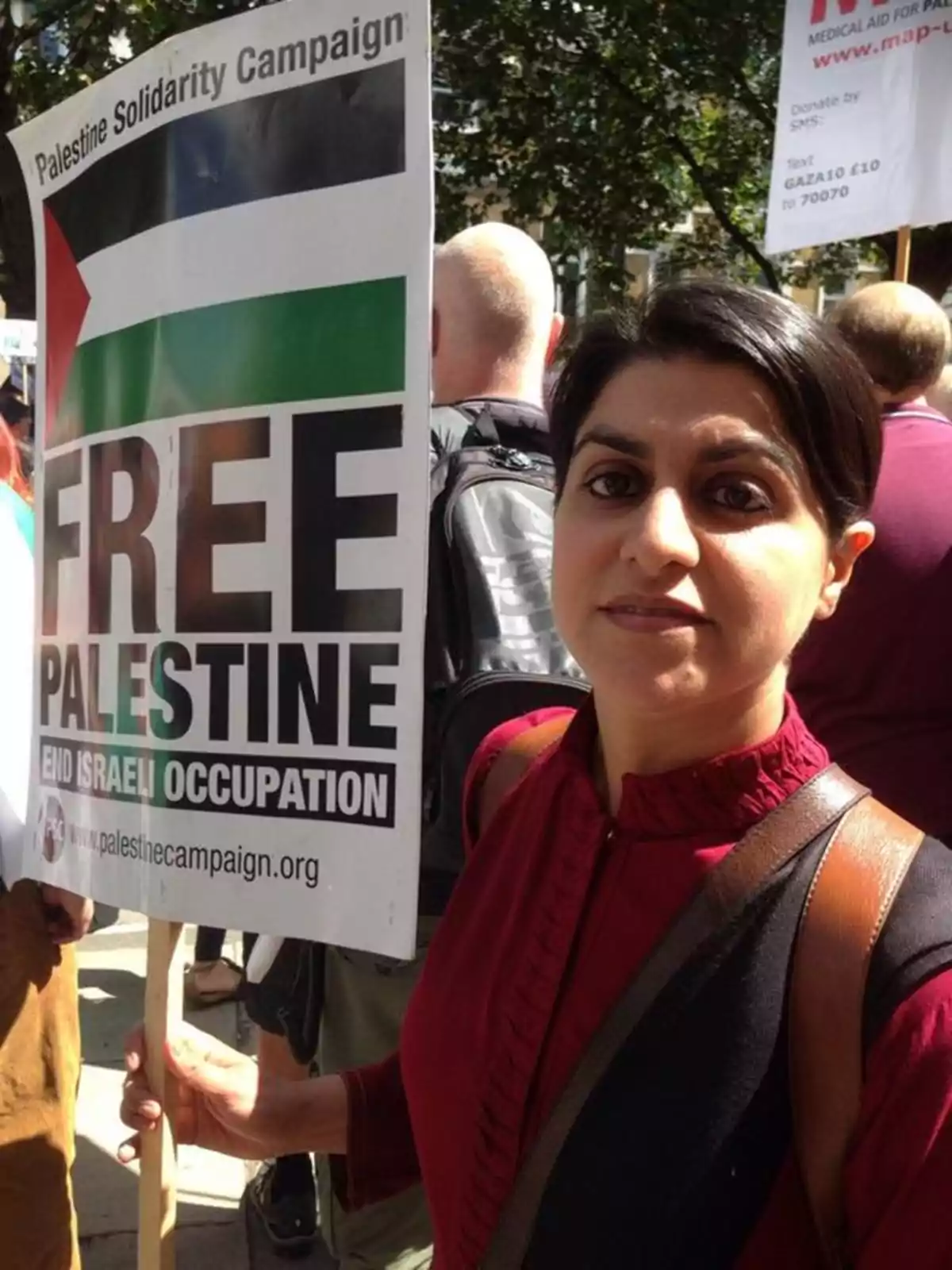 Woman in a red blouse holds a sign from the solidarity campaign with Palestine at an outdoor demonstration Woman in a red blouse holds a sign from the solidarity campaign with Palestine at an outdoor demonstration