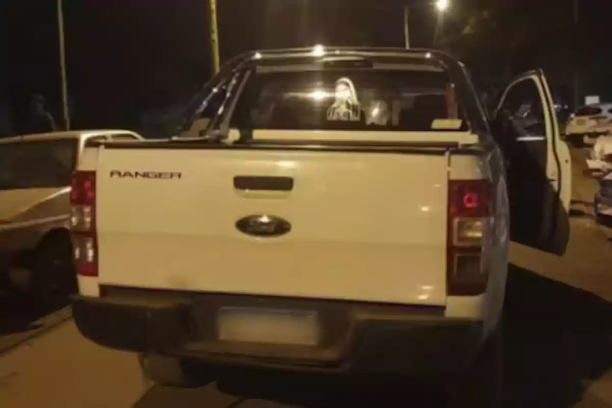 Camioneta Ford Ranger blanca estacionada de noche con la puerta trasera derecha abierta Camioneta Ford Ranger blanca estacionada de noche con la puerta trasera derecha abierta