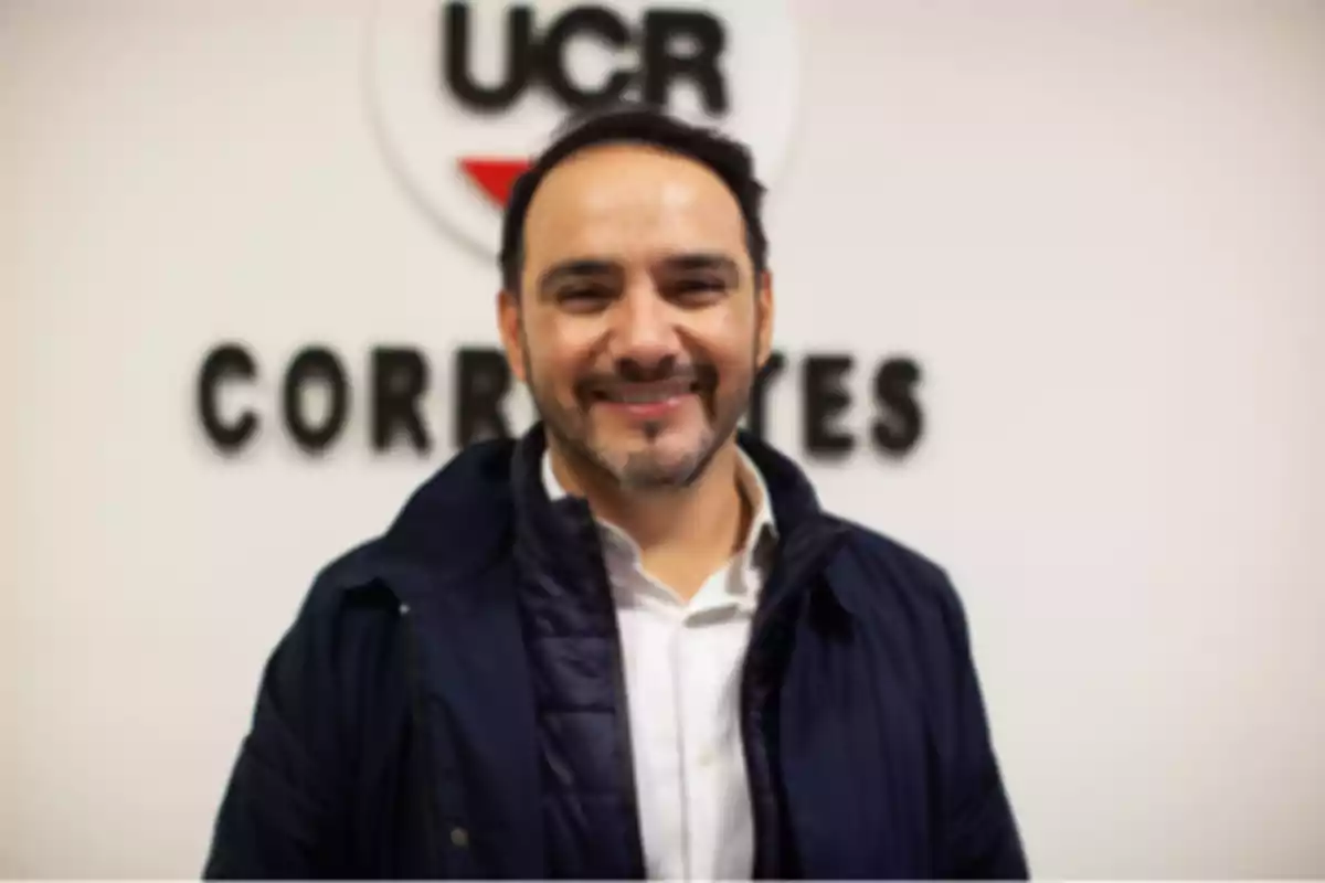 Smiling man with a beard and dark jacket posing in front of a blurred sign that says UCR Corrientes