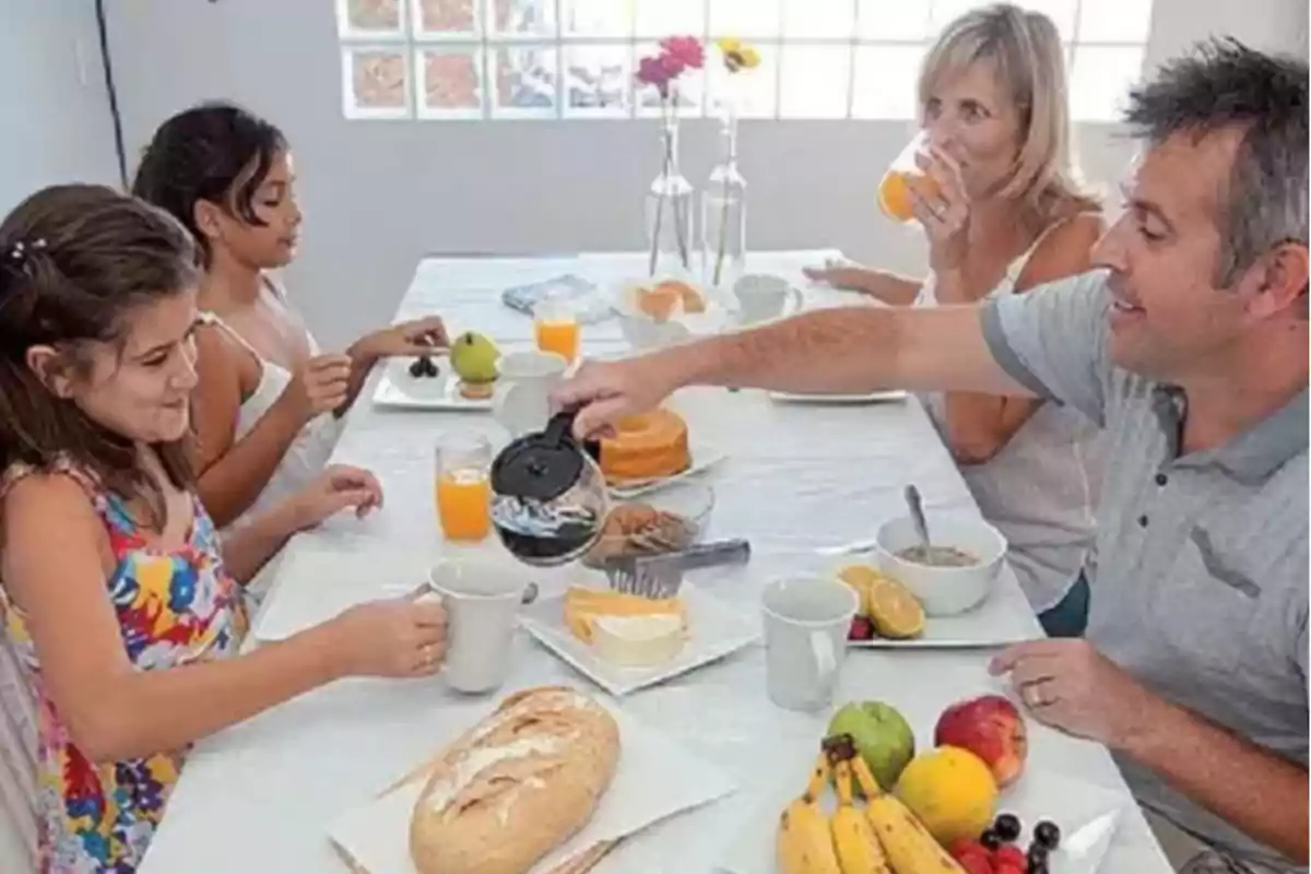 Family having breakfast together at a table with bread, fruit, juice, and coffee