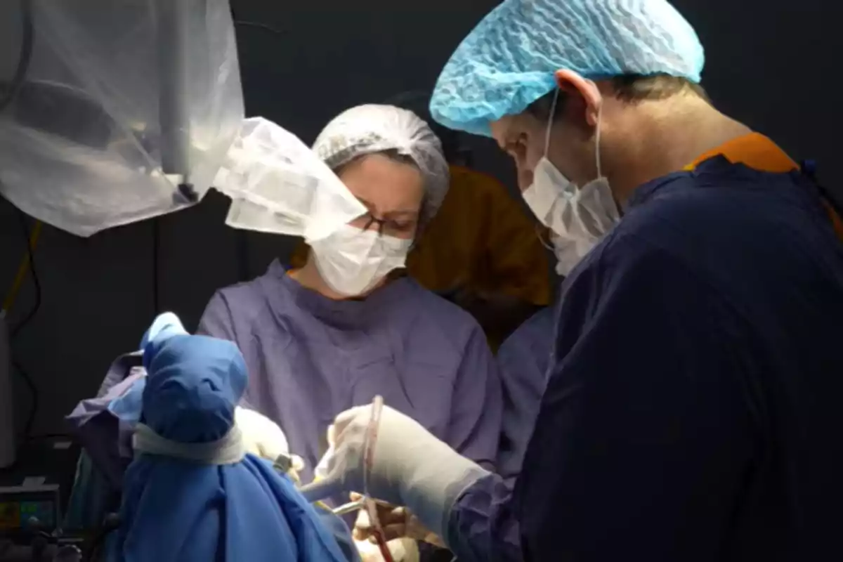 Cirujanos realizando una operación en un quirófano usando mascarillas y gorros quirúrgicos