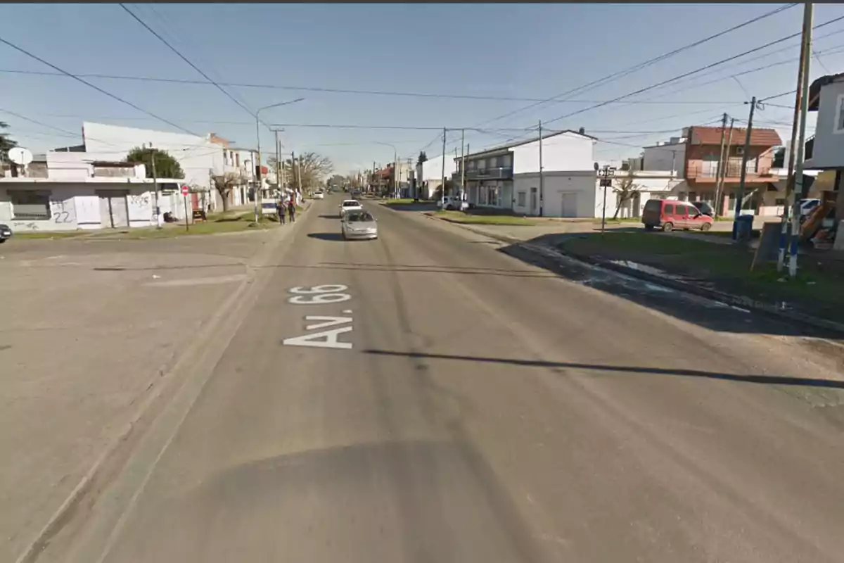 Wide avenue with houses and shops on both sides, cars driving by, and people walking on the sidewalk on a sunny day Wide avenue with houses and shops on both sides, cars driving by, and people walking on the sidewalk on a sunny day