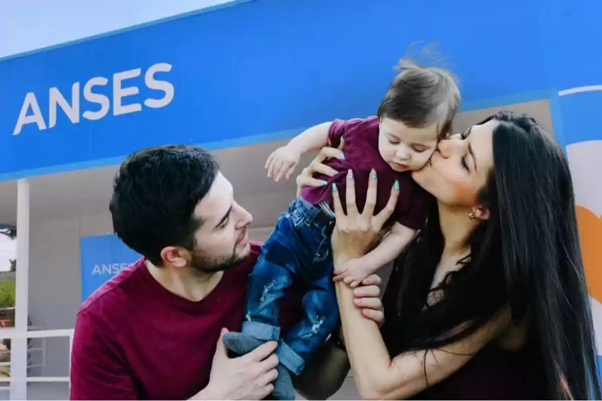 Una pareja sostiene y besa a un bebé frente a una oficina de ANSES Una pareja sostiene y besa a un bebé frente a una oficina de ANSES