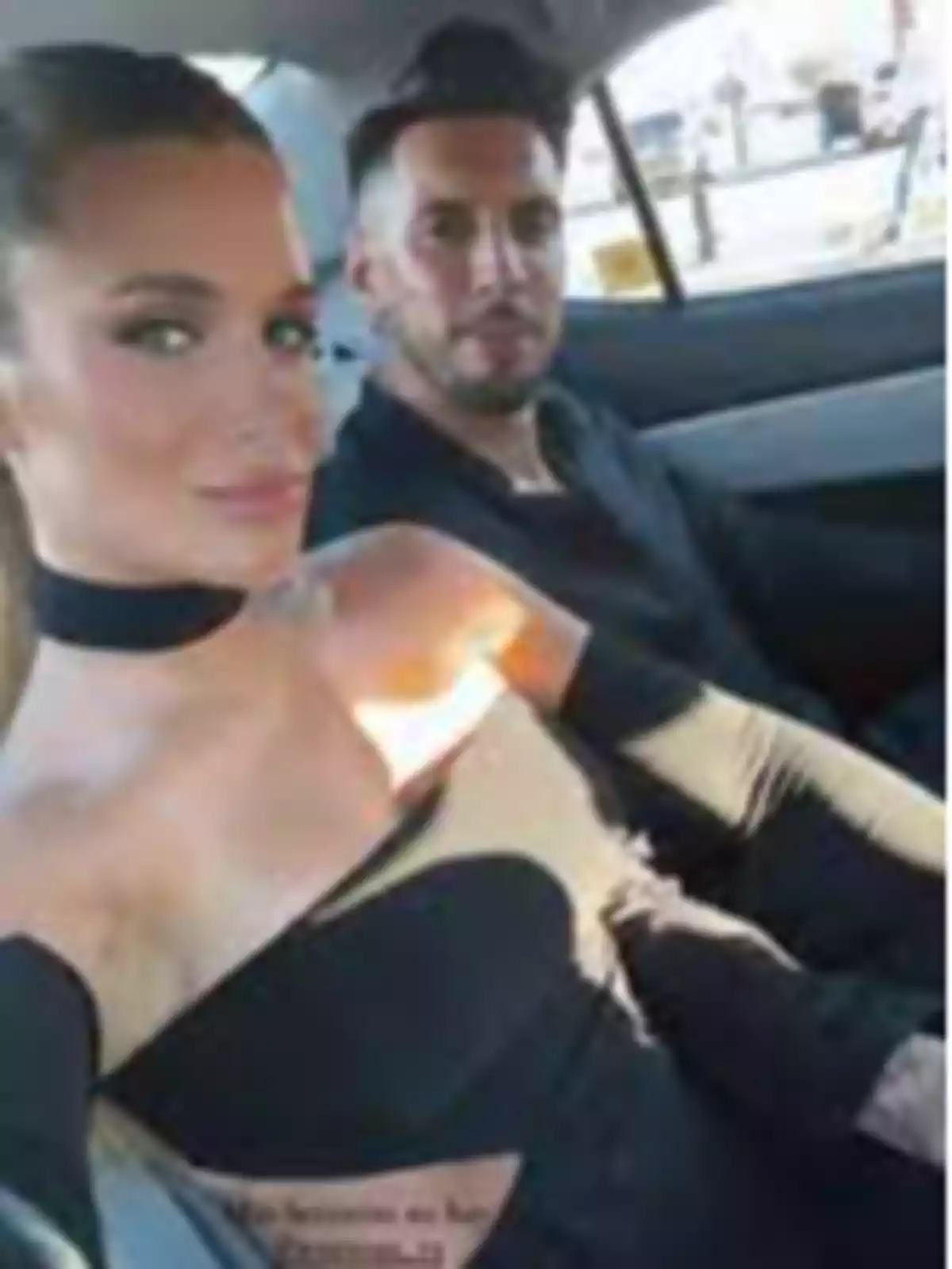 A couple sitting in the back seat of a car while looking at the camera A couple sitting in the back seat of a car while looking at the camera