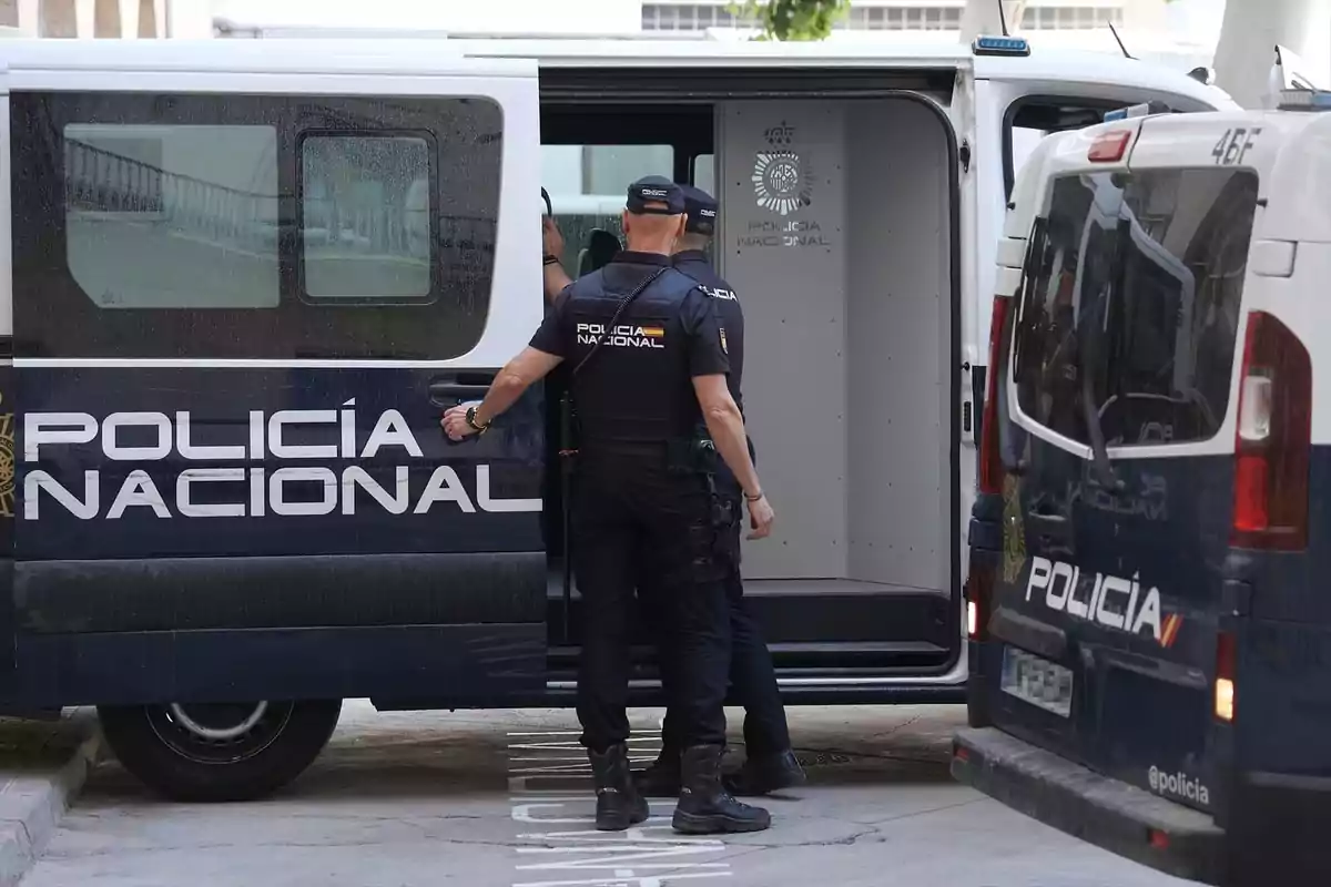 Two National Police officers next to a police van with the rear door open