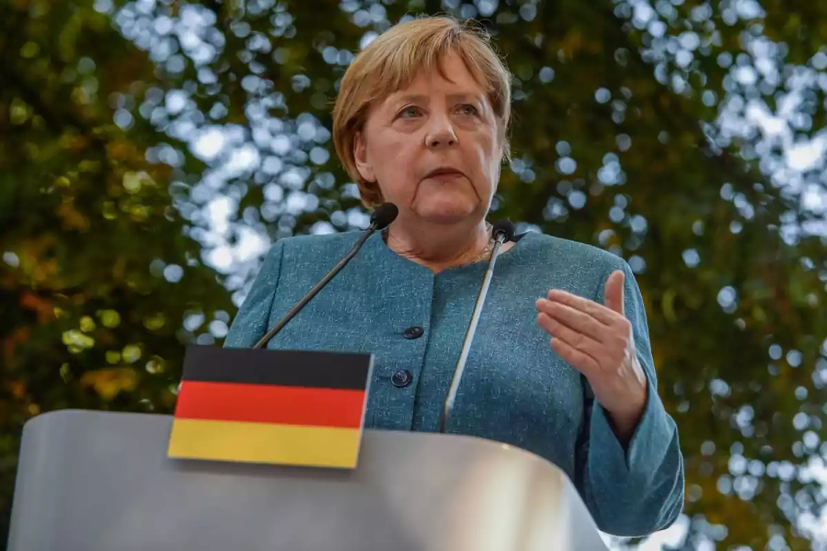 Short-haired blonde woman speaking at a podium with the German flag outdoors Short-haired blonde woman speaking at a podium with the German flag outdoors