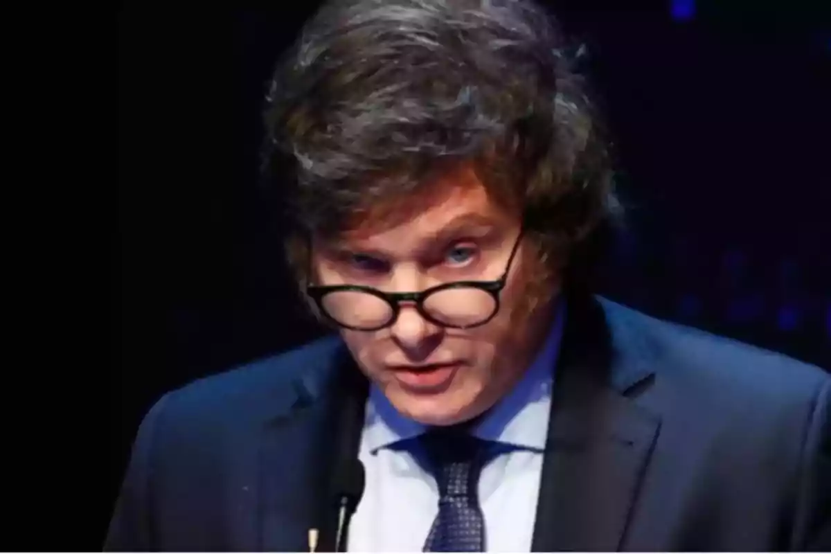 Brown-haired man with glasses looking forward with a serious expression while wearing a suit and tie Brown-haired man with glasses looking forward with a serious expression while wearing a suit and tie