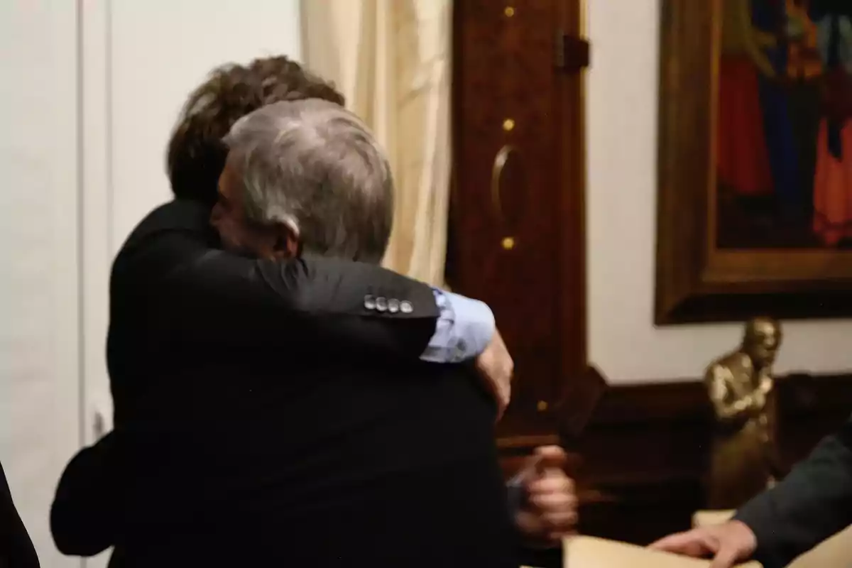 Dos personas se abrazan en una oficina elegante con una estatua y un cuadro al fondo Dos personas se abrazan en una oficina elegante con una estatua y un cuadro al fondo