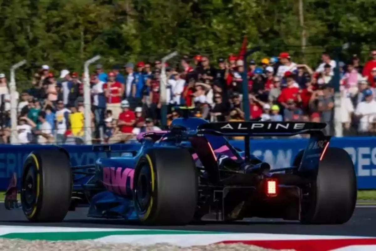 An Alpine Formula 1 single-seater drives on a racetrack with spectators in the background.