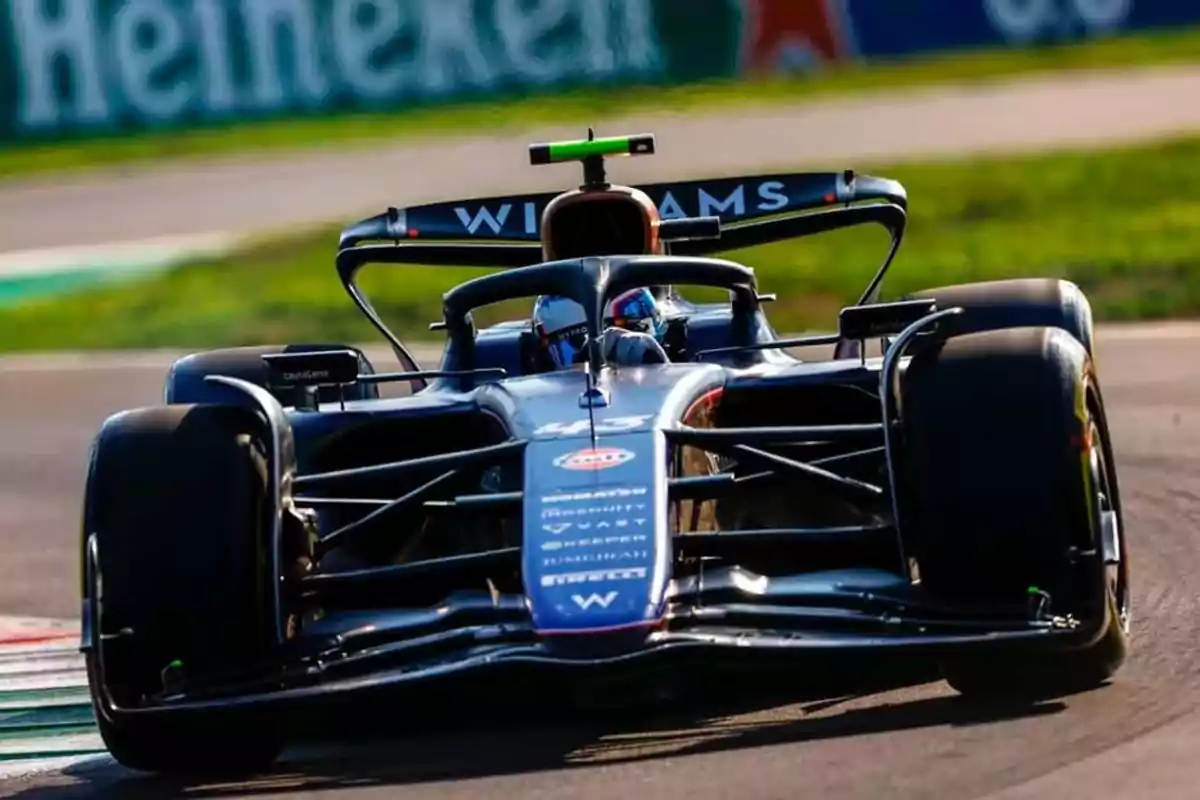 A Williams Formula 1 single-seater driving on a racetrack during the day. A Williams Formula 1 single-seater driving on a racetrack during the day.