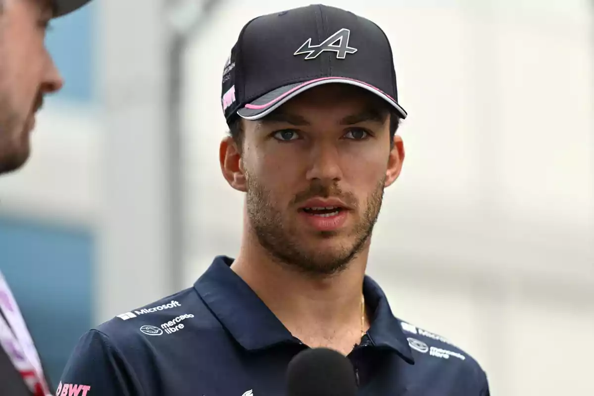 Young man with a beard and a black motorsport team cap speaking in front of a microphone