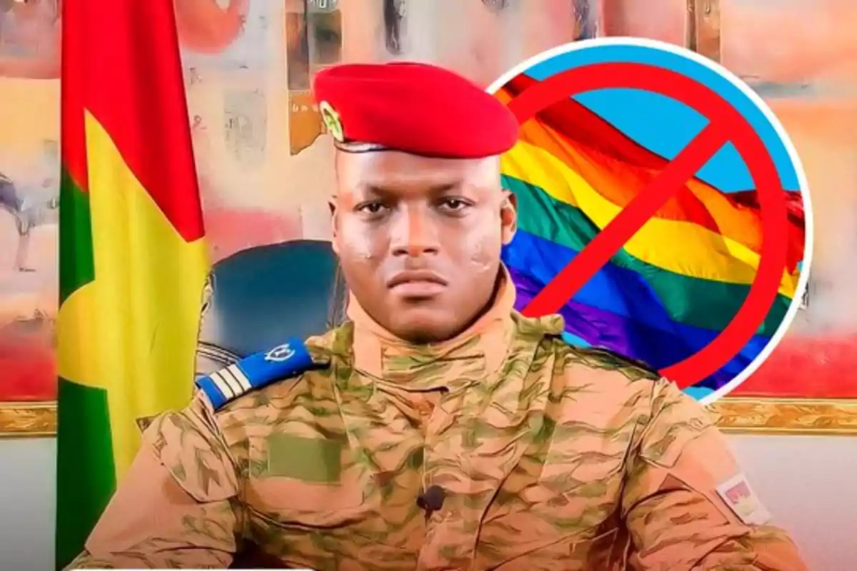 Militar con uniforme camuflado y boina roja sentado frente a una bandera, con un símbolo de prohibición sobre una bandera arcoíris al fondo