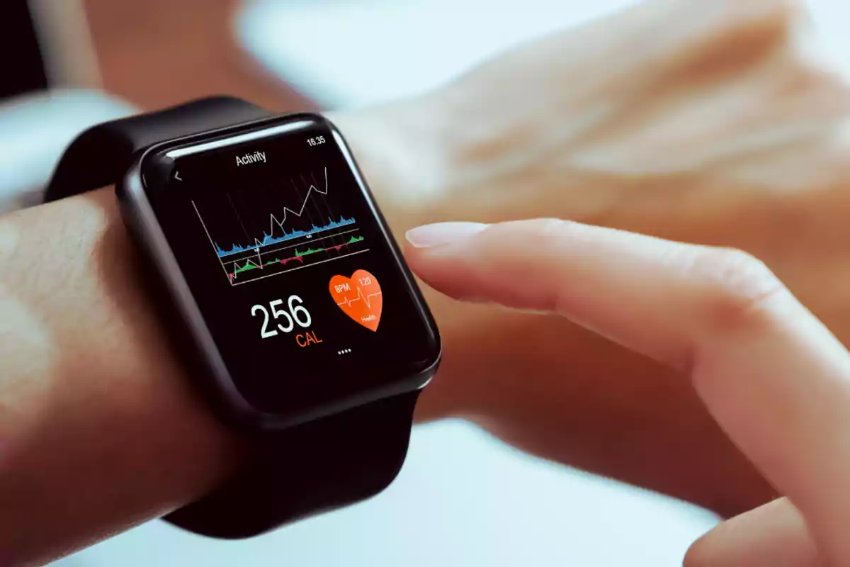 Persona usando un reloj inteligente que muestra datos de actividad física y frecuencia cardíaca en la pantalla. Persona usando un reloj inteligente que muestra datos de actividad física y frecuencia cardíaca en la pantalla.