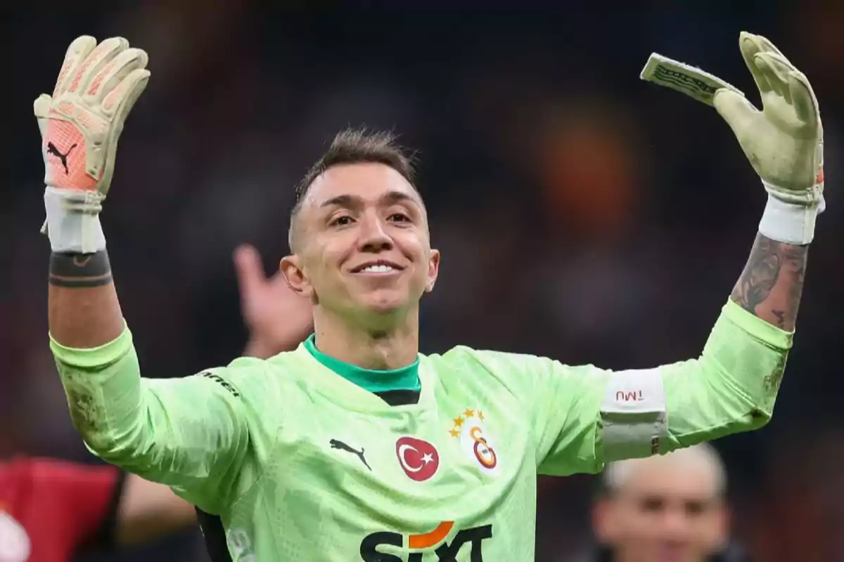 Soccer goalkeeper in a green uniform raising his arms and smiling on the field Soccer goalkeeper in a green uniform raising his arms and smiling on the field