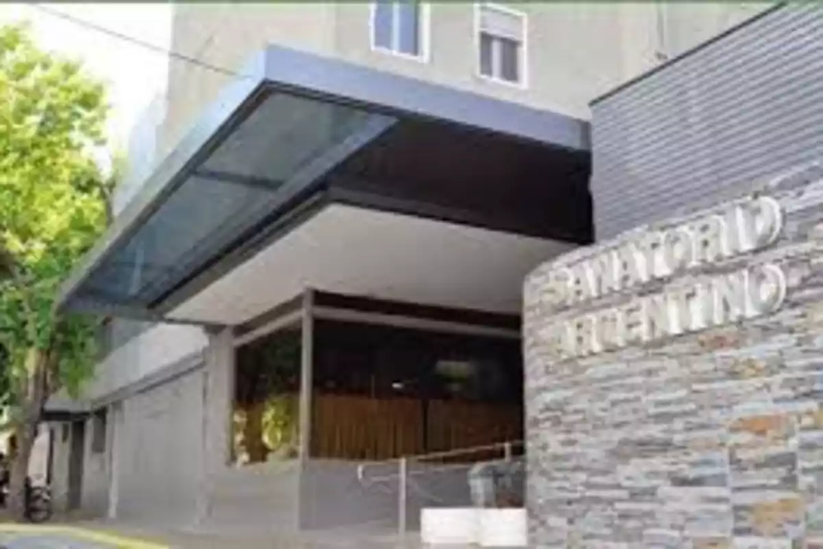 Main entrance of a sanatorium building with a sign that says Sanatorio Argentino and an access ramp Main entrance of a sanatorium building with a sign that says Sanatorio Argentino and an access ramp