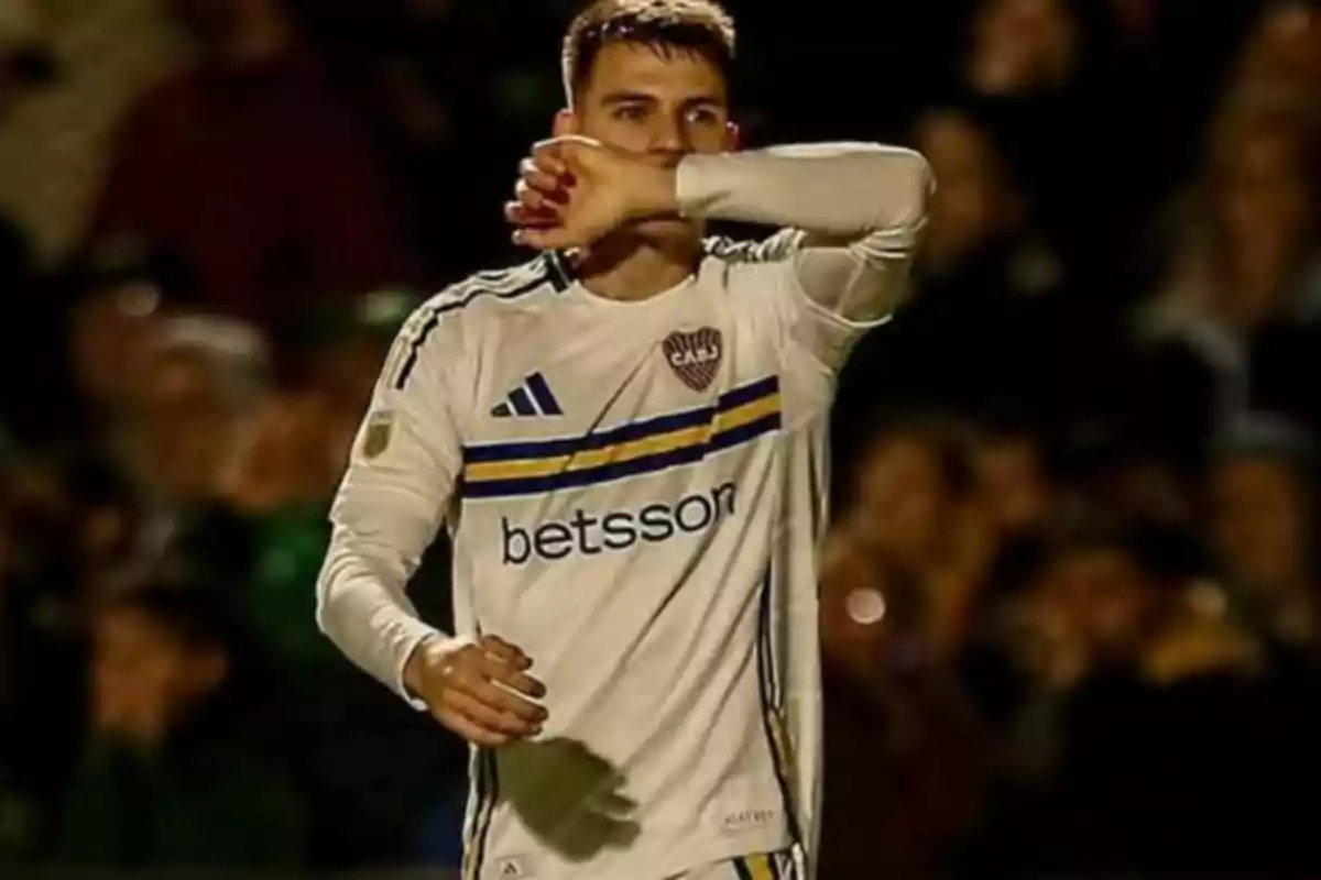 Futbolista con uniforme blanco de Boca Juniors celebrando un gol en un estadio lleno de público Futbolista con uniforme blanco de Boca Juniors celebrando un gol en un estadio lleno de público