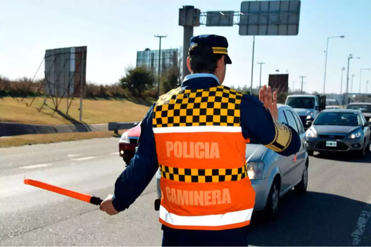 Traffic police officer stopping traffic on a road while holding an orange signaling light