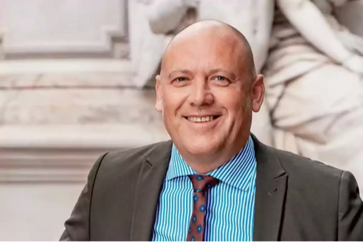 Bald man in a suit and tie smiles in front of a white background sculpture Bald man in a suit and tie smiles in front of a white background sculpture