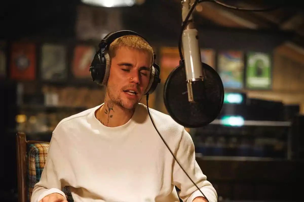 Young man with headphones and microphone singing in a recording studio