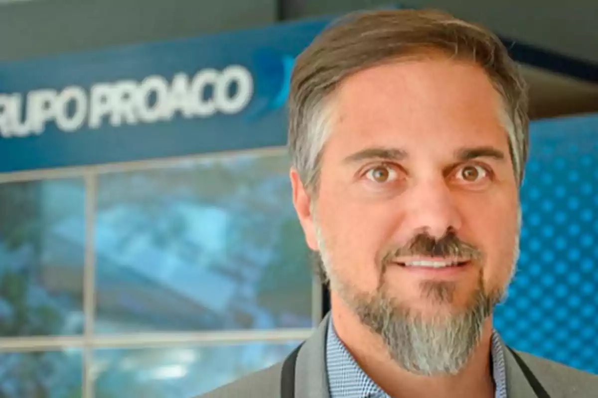 Man with gray hair and beard in front of a blue sign that says Grupo Proaco Man with gray hair and beard in front of a blue sign that says Grupo Proaco