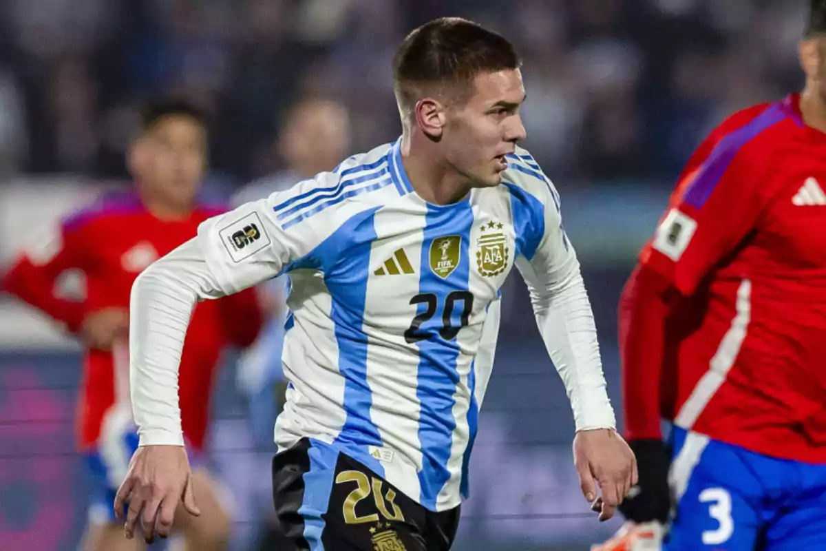 Futbolista de la selección argentina con el número 20 en la camiseta durante un partido contra un equipo con uniforme rojo. Futbolista de la selección argentina con el número 20 en la camiseta durante un partido contra un equipo con uniforme rojo.