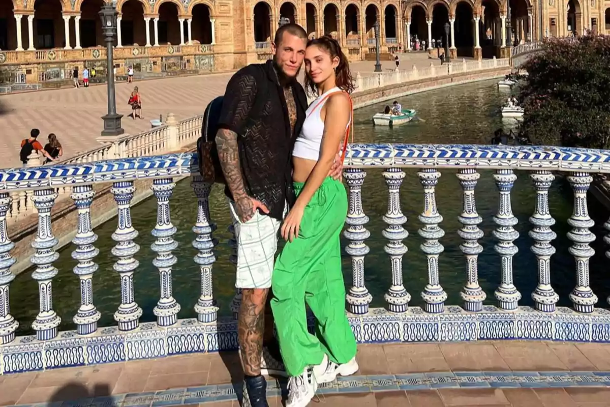 Young couple embracing, posing on a bridge decorated with blue and white ceramics at Plaza de España in Seville, with the canal and historic building in the background. Young couple embracing, posing on a bridge decorated with blue and white ceramics at Plaza de España in Seville, with the canal and historic building in the background.