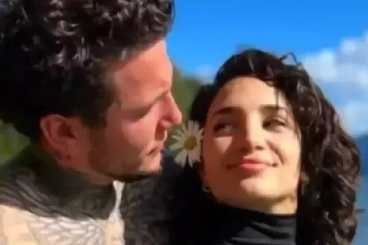 Couple hugging outdoors with a blue sky in the background and a white flower in the woman's hair Couple hugging outdoors with a blue sky in the background and a white flower in the woman's hair