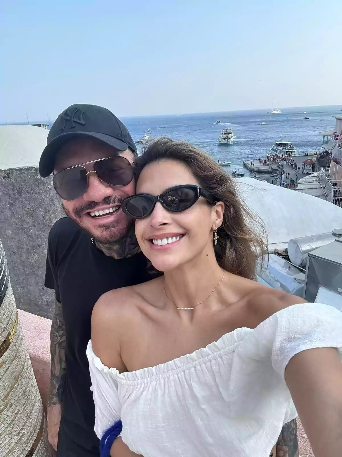 Smiling couple taking a selfie with the sea and several boats in the background on a sunny day Smiling couple taking a selfie with the sea and several boats in the background on a sunny day