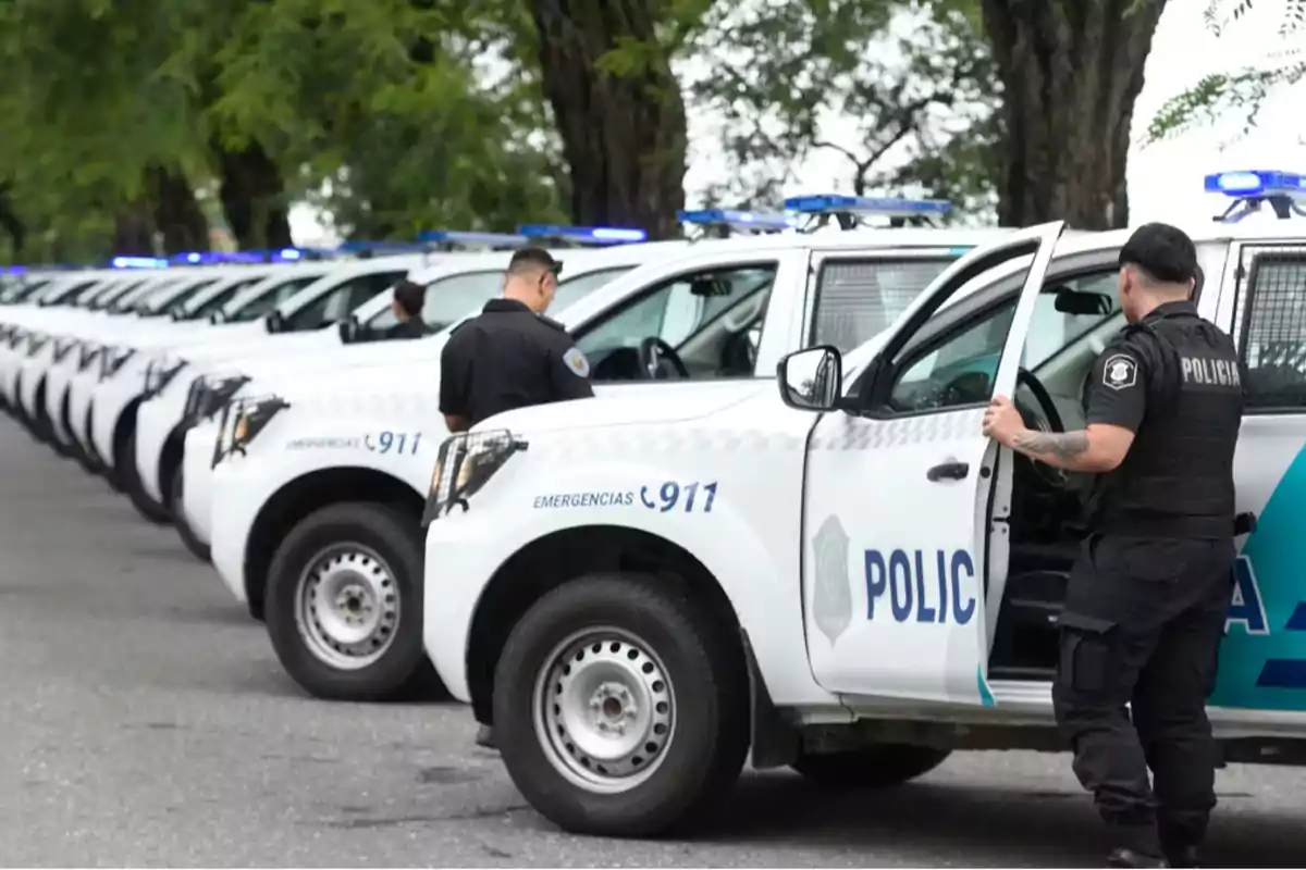 Varios patrulleros de policía alineados en la calle con agentes junto a los vehículos Varios patrulleros de policía alineados en la calle con agentes junto a los vehículos