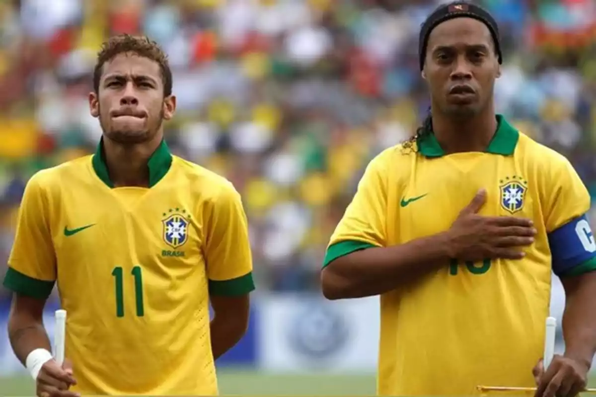 Two players from the Brazil national team in yellow uniforms during the national anthem in a stadium full of fans Two players from the Brazil national team in yellow uniforms during the national anthem in a stadium full of fans