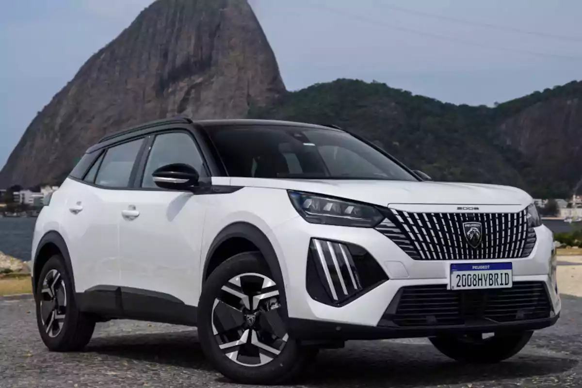 White hybrid Peugeot 2008 SUV parked in front of a mountainous landscape White hybrid Peugeot 2008 SUV parked in front of a mountainous landscape