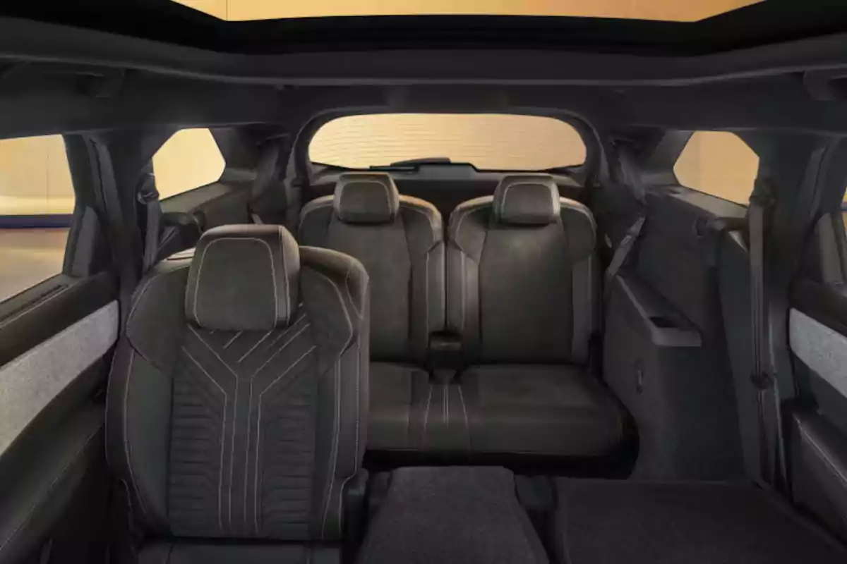 Interior of a vehicle with three rows of black seats and decorative stitching, viewed from the rear toward the front windshield Interior of a vehicle with three rows of black seats and decorative stitching, viewed from the rear toward the front windshield