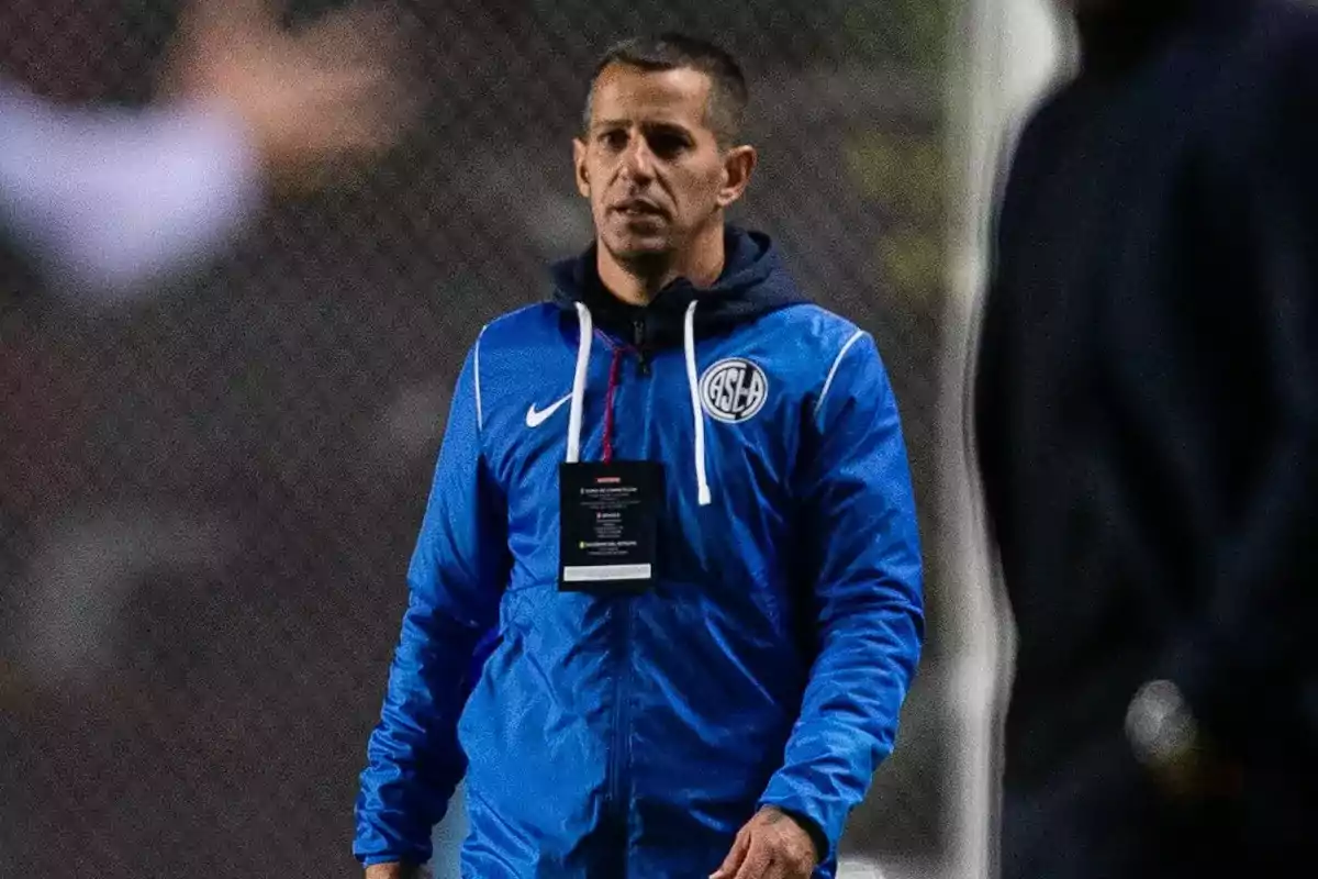 Entrenador de fútbol vistiendo campera azul de San Lorenzo en el campo de juego