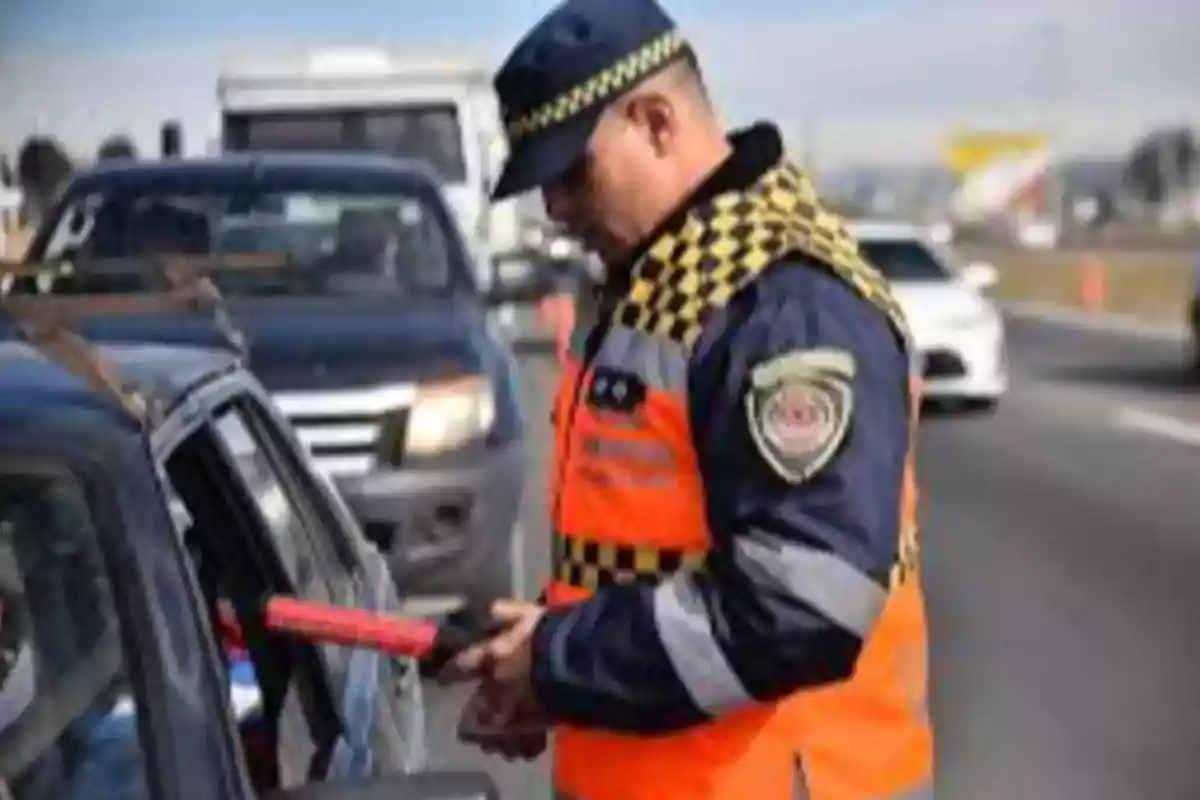 Oficial de tránsito revisando documentos de un conductor en un retén vial sobre una carretera Oficial de tránsito revisando documentos de un conductor en un retén vial sobre una carretera
