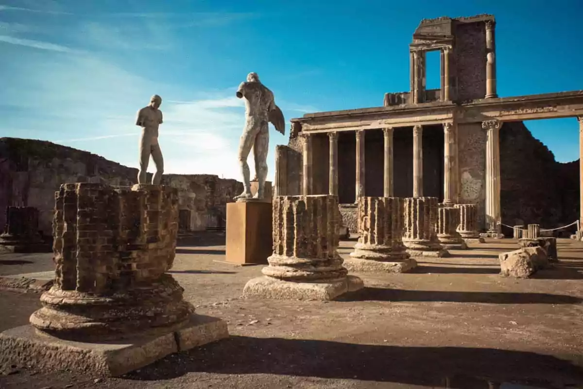 Ancient ruins with stone columns and statues under a blue sky Ancient ruins with stone columns and statues under a blue sky