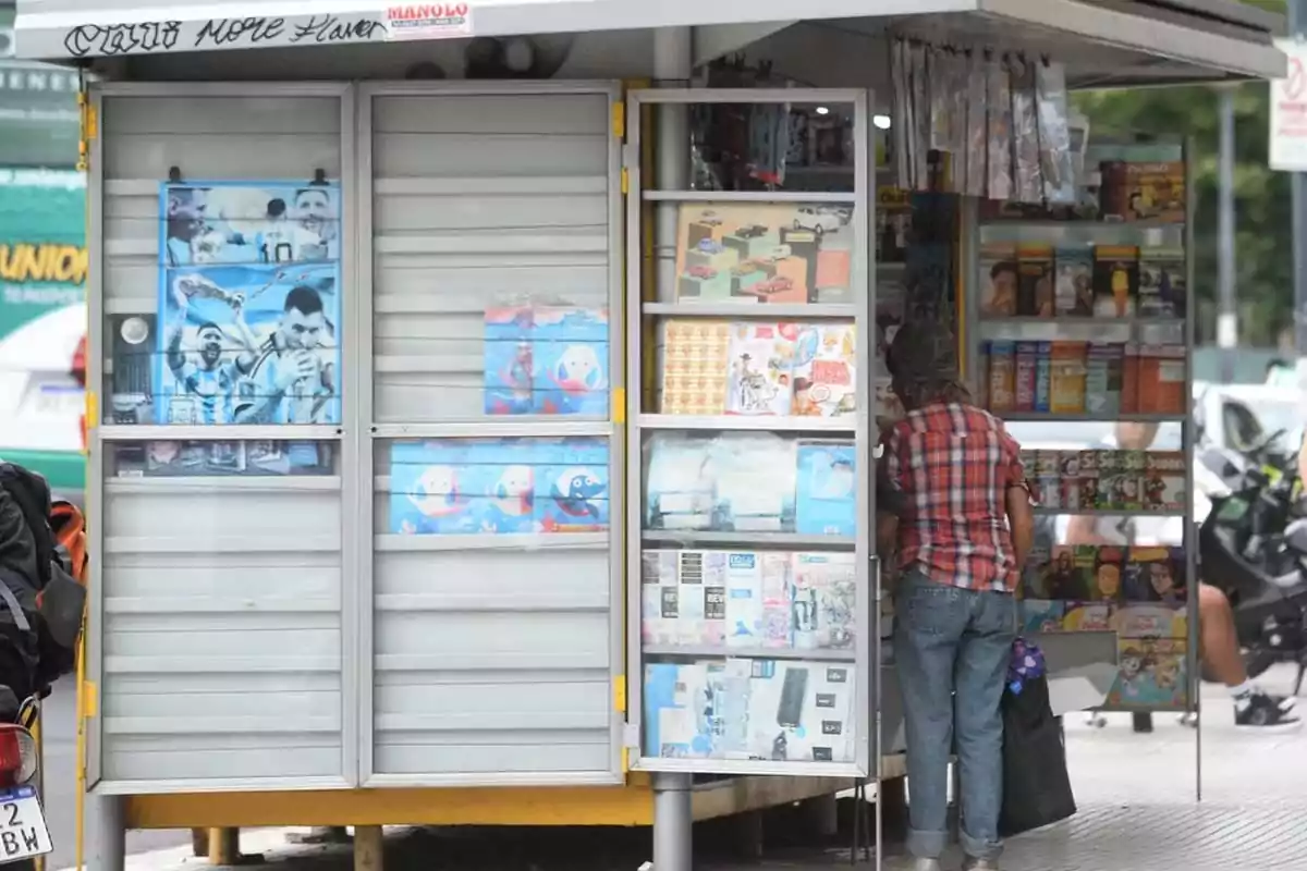 Newsstand on the street with a person facing away, looking through the publications Newsstand on the street with a person facing away, looking through the publications