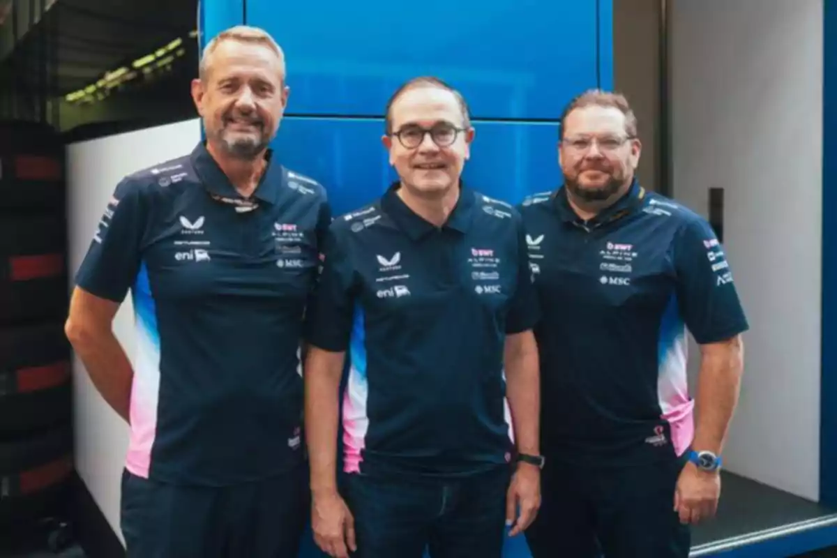 Three men in Alpine team uniforms pose together in front of a blue background. Three men in Alpine team uniforms pose together in front of a blue background.